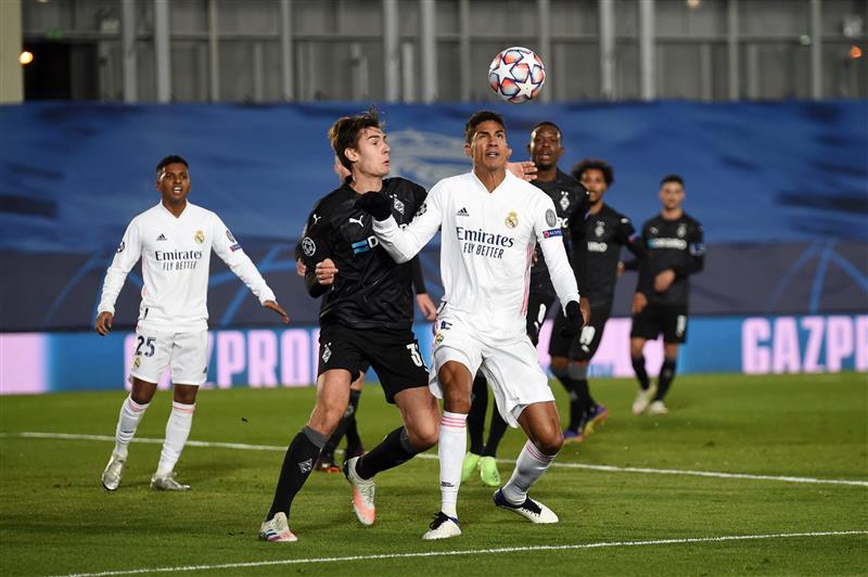 MADRID, SPAIN - DECEMBER 09: Raphael Varane of Real Madrid battles for possession with Florian Neuhaus of Borussia Moenchengladbach during the UEFA Champions League Group B stage match between Real Madrid and Borussia Moenchengladbach at Estadio Alfredo di Stefano on December 09, 2020 in Madrid, Spain. Sporting stadiums around Spain remain under strict restrictions due to the Coronavirus Pandemic as Government social distancing laws prohibit fans inside venues resulting in games being played behind closed doors. (Photo by Denis Doyle/Getty Images)