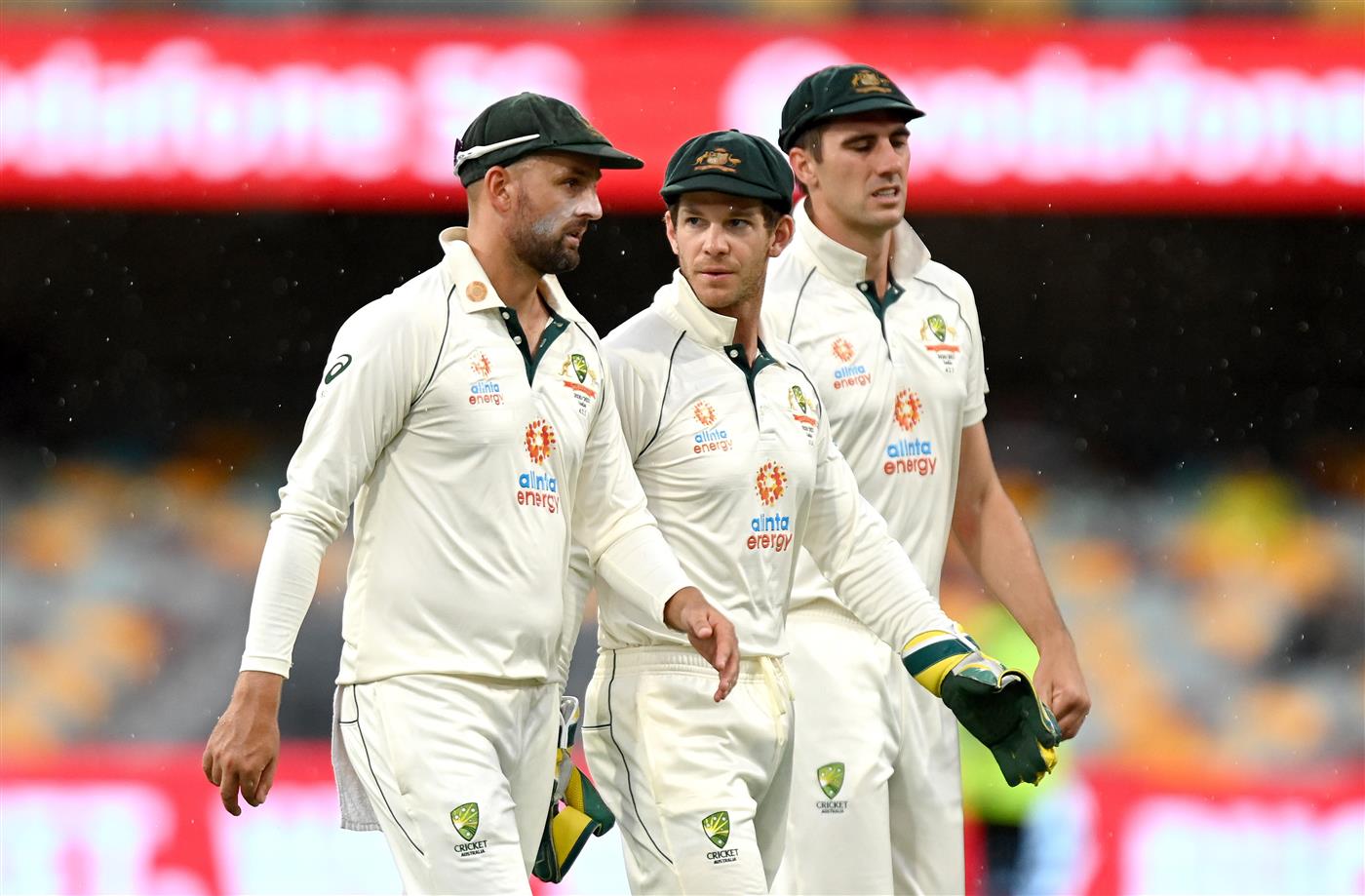 BRISBANE, AUSTRALIA - JANUARY 18: Tim Paine, Nathan Lyon and Pat Cummins of Australia are seen leaving the field as a rain delay is called during day four of the 4th Test Match in the series between Australia and India at The Gabba on January 18, 2021 in Brisbane, Australia. (Photo by Bradley Kanaris/Getty Images)