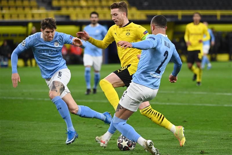 Dortmund's German forward Marco Reus (C) Manchester City's English defender John Stones (L) mand Manchester City's English defender Kyle Walker (R) vie for the ball during the UEFA Champions League quarter-final second leg football match between BVB Borussia Dortmund and Manchester City in Dortmund, western Germany, on April 14, 2021. (Photo by Ina Fassbender / various sources / AFP) (Photo by INA FASSBENDER/AFP via Getty Images)