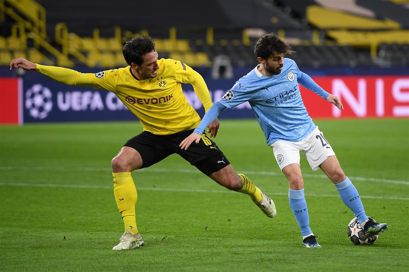 DORTMUND, GERMANY - APRIL 14: Bernardo Silva of Manchester City is challenged by Mats Hummels of Borussia Dortmund during the UEFA Champions League Quarter Final Second Leg match between Borussia Dortmund and Manchester City at Signal Iduna Park on April 14, 2021 in Dortmund, Germany. Sporting stadiums around Germany remain under strict restrictions due to the Coronavirus Pandemic as Government social distancing laws prohibit fans inside venues resulting in games being played behind closed doors.  (Photo by Frederic Scheidemann/Getty Images)