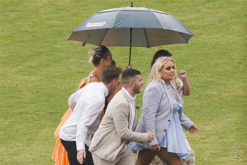 SYDNEY, AUSTRALIA - FEBRUARY 12: Racegoers take shelter from a rain shower during Sydney Racing at Royal Randwick Racecourse on February 12, 2022 in Sydney, Australia. (Photo by Jenny Evans/Getty Images)