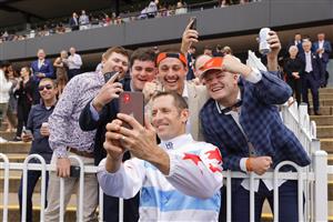 SYDNEY, AUSTRALIA - MARCH 19: Hugh Bowman poses with punters after winning race 7 The Agency George Ryder Stakes on Forbidden Love during Sydney Racing Longines Golden Slipper Day, at Rosehill Gardens on March 19, 2022 in Sydney, Australia. (Photo by Jenny Evans/Getty Images)
