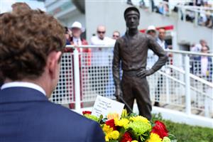 EPSOM, ENGLAND - JUNE 03: Jockey Ryan Moore prepares to lay at wreath at the base of the Lester Piggott statue following Piggott's recent passing during Ladies Day at Epsom Racecourse on June 03, 2022 in Epsom, England. (Photo by Andrew Redington/Getty Images)