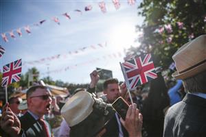 ASCOT, ENGLAND - JUNE 14: Racegoers wave Union Jack flags during the sing-along at the end of the first day of Royal Ascot 2022 at Ascot Racecourse on June 14, 2022 in Ascot, England. (Photo by John Phillips/Getty Images for Ascot Racecourse)