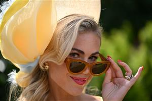 A race-goer wearing a hat poses upon her arrival to attend the third day, known as the Lady