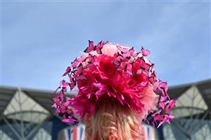 A race-goer wearing a hat arrives to attend the third day, known as the Lady