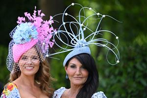 Race-goers wearing hats pose upon their arrival to attend the third day, known as the Lady