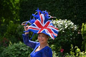 A race-goer wearing a hat poses upon her arrival to attend the third day, known as the Lady