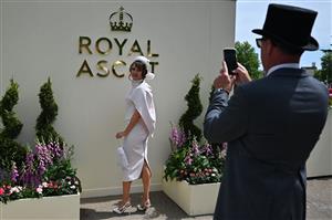 A race-goer poses upon her arrival to attend the third day, known as the Lady