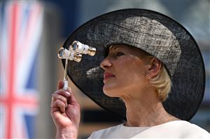 A race-goer wearing a hat poses upon her arrival to attend the third day, known as the Lady