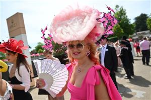 A race-goer wearing a hat arrives to attend the third day, known as the Lady