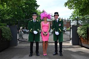 A race-goer poses with Ascot Greencoat stewards upon her arrival to attend the third day, known as the Lady