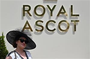 A race-goer poses for pictures as she attends the third day, known as the Lady