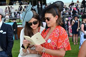 Racegoers consult their racecard on the third day, known as the Lady