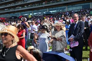 Racegoers cheers on their selections in the summer sunshine as a race finishes on the third day, known as the Lady