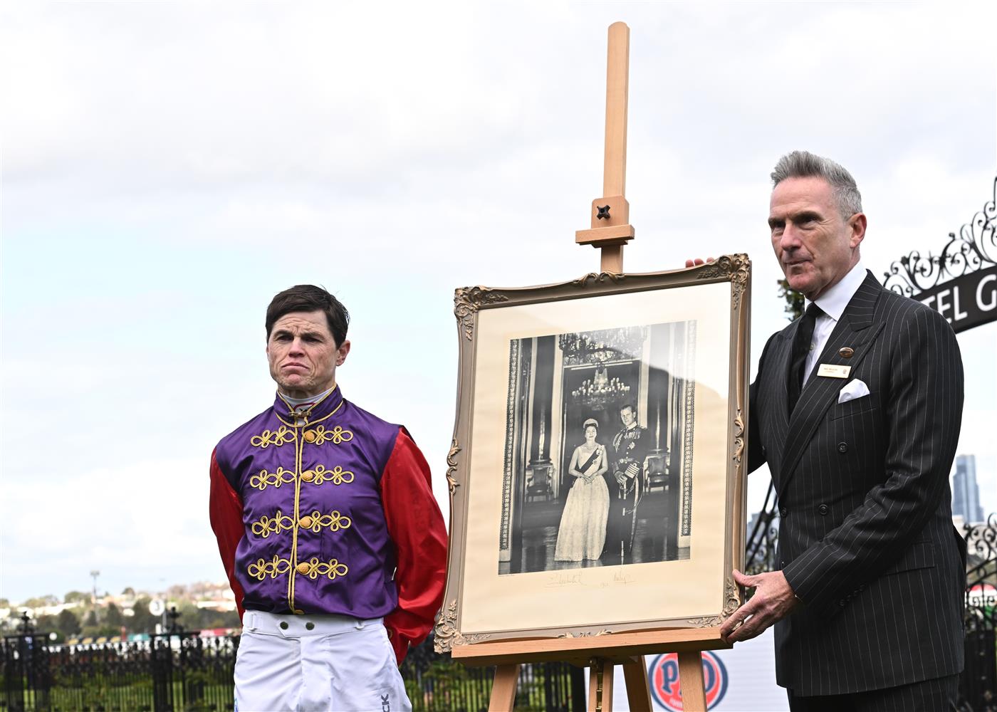 MELBOURNE, AUSTRALIA - SEPTEMBER 10: Craig Williams is seen in Her Majesty Queen Elizabeth II racing colours while posing with VRC Chairman, Neil Wilson, after Jockeys and officials observed a minutes silence in memory of Her Majesty Queen Elizabeth II, during Melbourne Racing at Flemington Racecourse on September 10, 2022 in Melbourne, Australia. (Photo by Vince Caligiuri/Getty Images)