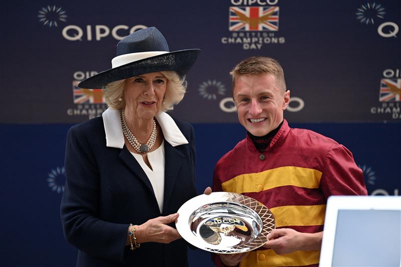 Britain's Camilla, Queen Consort (L) poses for a photograph with British jockey Tom Marquand (R) winner of the Queen Elizabeth II Stakes on Qipco British Champions Day at Ascot Racecourse, west of London on October 15, 2022. - Champions day is the finale of the British flat racing season and the UK's richest raceday. (Photo by Glyn KIRK / AFP) (Photo by GLYN KIRK/AFP via Getty Images)
