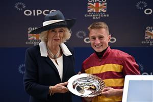 Britain's Camilla, Queen Consort (L) poses for a photograph with British jockey Tom Marquand (R) winner of the Queen Elizabeth II Stakes on Qipco British Champions Day at Ascot Racecourse, west of London on October 15, 2022. - Champions day is the finale of the British flat racing season and the UK's richest raceday. (Photo by Glyn KIRK / AFP) (Photo by GLYN KIRK/AFP via Getty Images)