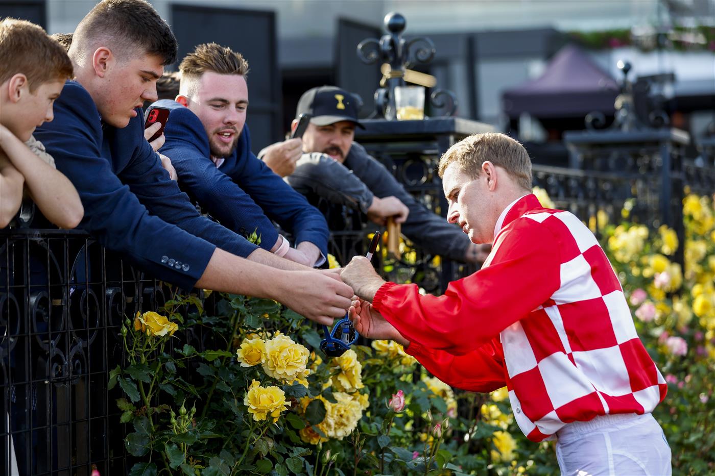 MELBOURNE, AUSTRALIA - NOVEMBER 03: Jockey Tommy Berry signs a pair of goggles during 2022 Oaks Day at Flemington Racecourse on November 03, 2022 in Melbourne, Australia. (Photo by Luke Hemer/Getty Images for VRC)