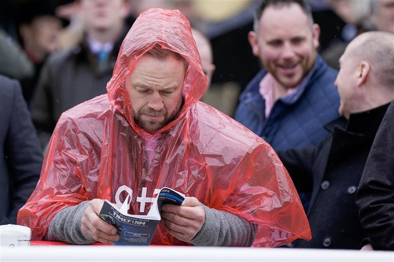 CHELTENHAM, ENGLAND - MARCH 15: A racegoer takes protection from the rain during day two of the Cheltenham Festival 2023 at Cheltenham Racecourse on March 15, 2023 in Cheltenham, England. (Photo by Alan Crowhurst/Getty Images)