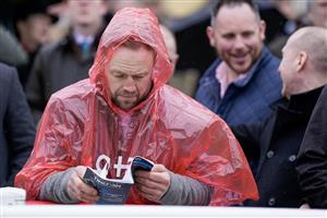 CHELTENHAM, ENGLAND - MARCH 15: A racegoer takes protection from the rain during day two of the Cheltenham Festival 2023 at Cheltenham Racecourse on March 15, 2023 in Cheltenham, England. (Photo by Alan Crowhurst/Getty Images)