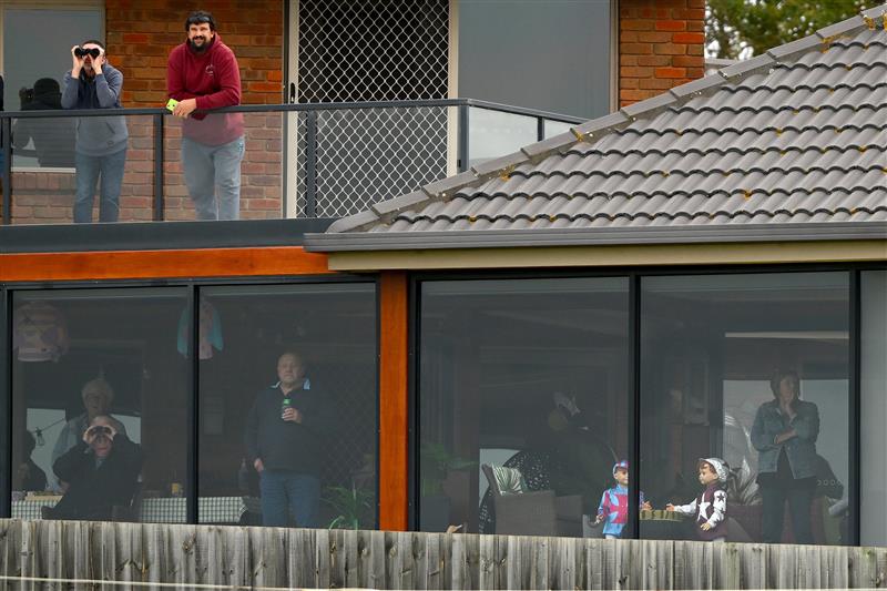 WARRNAMBOOL, AUSTRALIA - MAY 04: Crowds watch the Brandt Grand Annual Steeplechase from a home during Grand Annual Day at Warrnambool Racing Club on May 04, 2023 in Warrnambool, Australia. (Photo by Morgan Hancock/Getty Images)