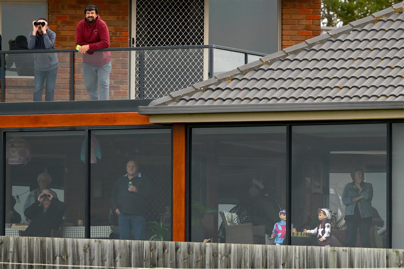 WARRNAMBOOL, AUSTRALIA - MAY 04: Crowds watch the Brandt Grand Annual Steeplechase from a home during Grand Annual Day at Warrnambool Racing Club on May 04, 2023 in Warrnambool, Australia. (Photo by Morgan Hancock/Getty Images)