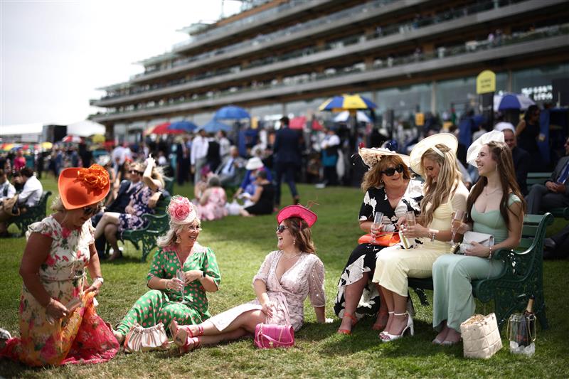 TOPSHOT - Racegoers relax in front of the grandstand ahead of racing on the fourth day of the Royal Ascot horse racing meeting in Ascot, west of London, on June 23, 2023. (Photo by HENRY NICHOLLS / AFP) (Photo by HENRY NICHOLLS/AFP via Getty Images)