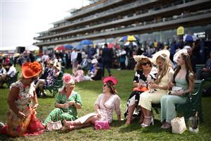 TOPSHOT - Racegoers relax in front of the grandstand ahead of racing on the fourth day of the Royal Ascot horse racing meeting in Ascot, west of London, on June 23, 2023. (Photo by HENRY NICHOLLS / AFP) (Photo by HENRY NICHOLLS/AFP via Getty Images)
