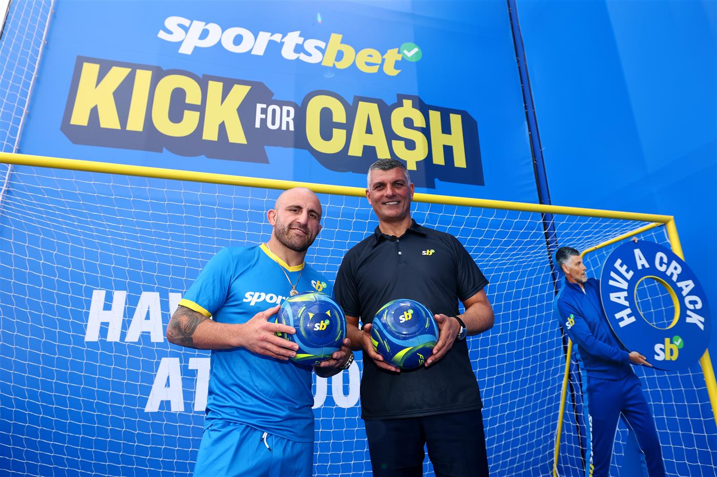 MELBOURNE, AUSTRALIA - OCTOBER 11: UFC fighter Alexander Volkanovski and John Aloisi pose during the Sportsbet Kick for Cash event at Caulfield Racecourse, celebrating the 20th anniversary of John Aloisi kicking the winning penalty that qualified Australia for the 2006 World Cup. (Getty)