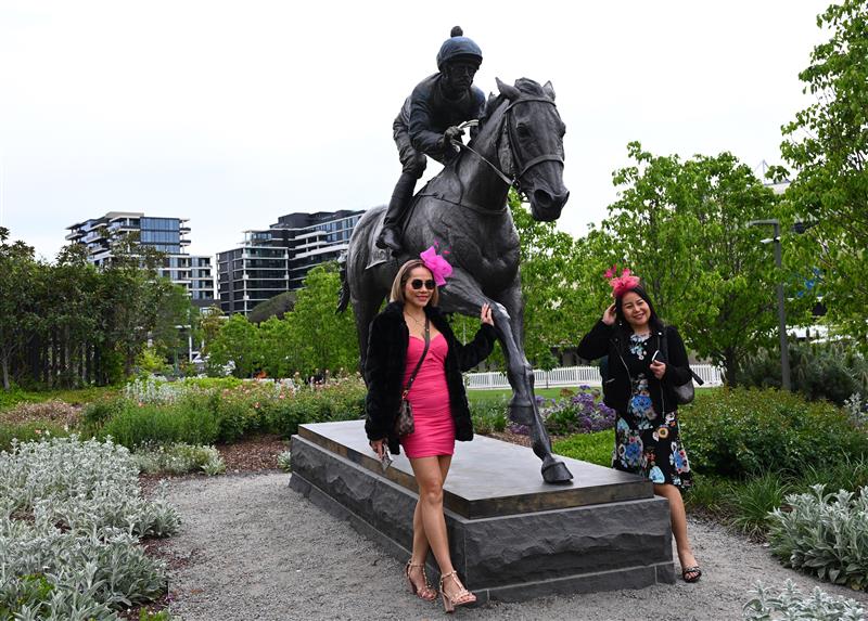 MELBOURNE, AUSTRALIA - OCTOBER 25: Racegoers pose in front of the Winx statue during Cox Plate Day at Moonee Valley Racecourse on October 25, 2025 in Melbourne, Australia. (Photo by Vince Caligiuri/Getty Images)