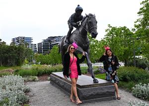 MELBOURNE, AUSTRALIA - OCTOBER 25: Racegoers pose in front of the Winx statue during Cox Plate Day at Moonee Valley Racecourse on October 25, 2025 in Melbourne, Australia. (Photo by Vince Caligiuri/Getty Images)
