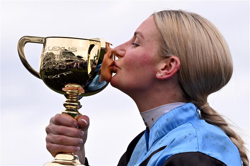 Australian jockey Jamie Melham kisses the trophy after riding Half Yours to victory in the Melbourne Cup horse race at the Flemington Racecourse in Melbourne on November 4, 2025. Melham became only the second woman jockey to win the Aus$10 million (US$6.5 million) Melbourne Cup on November 4, steering Half Yours to victory in Australia