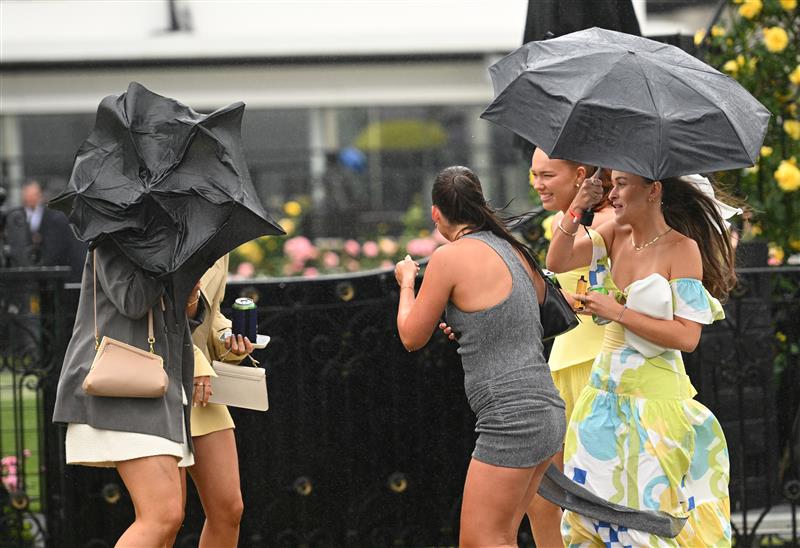 MELBOURNE, AUSTRALIA - NOVEMBER 08: Young racegoers are seen in the rain during Champions Day at Flemington Racecourse on November 08, 2025 in Melbourne, Australia. (Photo by Vince Caligiuri/Getty Images)