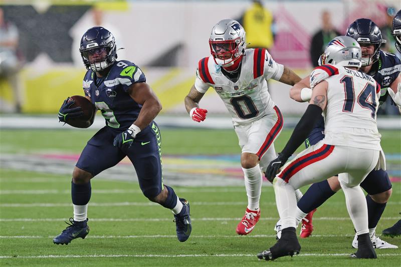 SANTA CLARA, CALIFORNIA - FEBRUARY 08: Kenneth Walker III #9 of the Seattle Seahawks rushes as Christian Gonzalez #0 of the New England Patriots pursues during the third quarter of Super Bowl LX at Levi