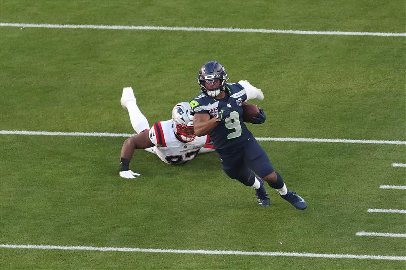 SANTA CLARA, CALIFORNIA - FEBRUARY 08: Kenneth Walker III #9 of the Seattle Seahawks breaks a tackle against Milton Williams #97 of the New England Patriots during the second quarter in  Super Bowl LX at Levi