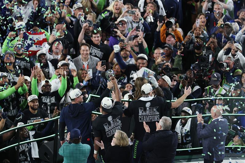 SANTA CLARA, CALIFORNIA - FEBRUARY 08: Head coach Mike MacDonald, Kenneth Walker III #9 and Sam Darnold #14 of the Seattle Seahawks celebrate with the Vince Lombardi Trophy after winning Super Bowl LX against the New England Patriots at Levi
