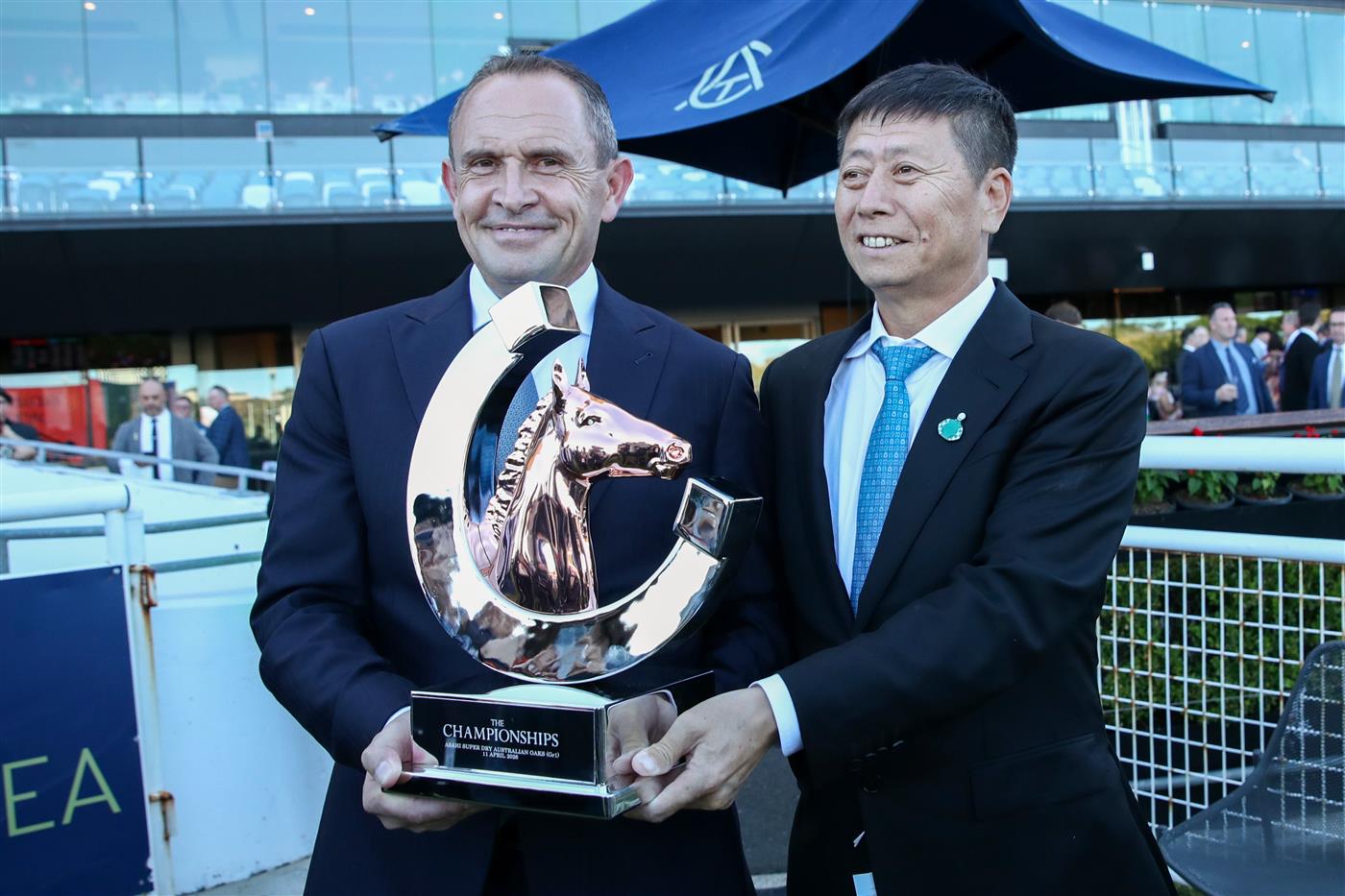 SYDNEY, AUSTRALIA - APRIL 11: Yuesheng Zhang owner of Ohope Wins along side trainer Chris Waller celebrate winning Race 5 The Asahi Super Dry Australian Oaks during Sydney Racing at Royal Randwick Racecourse on April 11, 2026 in Sydney, Australia. (Photo by Jason McCawley/Getty Images)