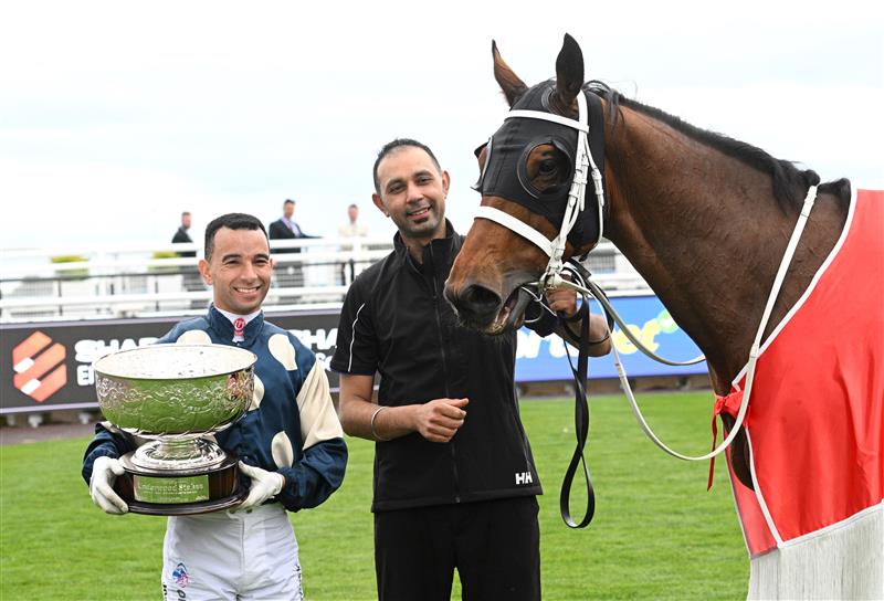MELBOURNE, AUSTRALIA - SEPTEMBER 21: Joao Moreira poses with the trophy and strapper (r) after riding Buckaroo to wi Race 8, the Henley Homes Underwood Stakes - Betting Odds during Melbourne Racing at Caulfield Racecourse on September 21, 2024 in Melbourne, Australia. (Photo by Vince Caligiuri/Getty Images)