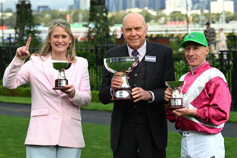 MELBOURNE, AUSTRALIA - OCTOBER 03: William Pike poses with trophy with trainer Andrea Leek (L) and owner Bob Peters after riding Cosmic Crusader to win race 8, the Tab Turnbull Stakes  during Turnbull Stakes Day at Flemington Racecourse on October 03, 2026 in Melbourne, Australia. (Photo by Vince Caligiuri/Getty Images)