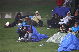TAURANGA, NEW ZEALAND - NOVEMBER 30: People shelter from the rain as they wait for play to resume during game three of the International Twenty20 series between New Zealand and the West Indies at Bay Oval on November 30, 2020 in Tauranga, New Zealand. (Photo by Phil Walter/Getty Images)