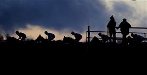 WINCANTON, ENGLAND - DECEMBER 03: Two stable staff look on as the runners in The Free Entry With Racing TV Club Days 'Junior' Standard Open NH Flat Race pass the grandstands at Wincanton Racecourse on December 03, 2020 in Wincanton, England. Owners and a limited number of the public are allowed to attend the meeting due to the Coronavirus pandemic. (Photo by Alan Crowhurst/Getty Images)