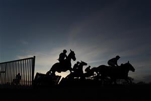 FONTWELL, ENGLAND - DECEMBER 08: A general view as runners in the last race of the day clear a flight of hurdles during The John And Maryanne Birch Memorial Handicap Hurdle as the sun begins to set at Fontwell Park Racecourse on December 08, 2020 in Fontwell, England. Owners and a limited number of the public are allowed to attend the meeting due to the Coronavirus pandemic. (Photo by Alan Crowhurst/Getty Images)