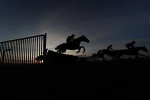 FONTWELL, ENGLAND - DECEMBER 08: A general view as runners in the last race of the day clear a flight of hurdles during The John And Maryanne Birch Memorial Handicap Hurdle as the sun begins to set at Fontwell Park Racecourse on December 08, 2020 in Fontwell, England. Owners and a limited number of the public are allowed to attend the meeting due to the Coronavirus pandemic. (Photo by Alan Crowhurst/Getty Images)