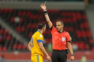 Uruguayan referee Esteban Ostojich (R) presents a yellow card to Tigres