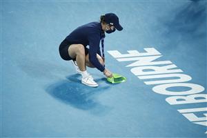 MELBOURNE, AUSTRALIA - FEBRUARY 16: An Australian staff member cleans up fragments of broken racquet after Novak Djokovic of Serbia smashed it in his Men