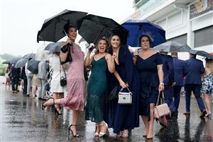 EPSOM, ENGLAND – JUNE 4: Racegoers use umbrellas to shelter from the rain during day one of the Cazoo Derby Festival at Epsom Racecourse on June 4, 2021 in Epsom, England. (Photo by John Walton-Pool/Getty Images)