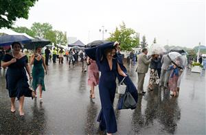 EPSOM, ENGLAND – JUNE 4: Racegoers try to shelter from the rain during day one of the Cazoo Derby Festival at Epsom Racecourse on June 4, 2021 in Epsom, England. (Photo by John Walton-Pool/Getty Images)