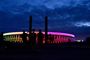 People look at the Olympic stadium as it is illuminated with the Rainbow colours, in Berlin, eastern Germany, on June 23, 2021. (Getty Images)