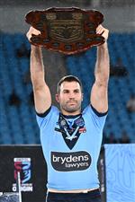 GOLD COAST, AUSTRALIA - JULY 14: James Tedesco of the Blues holds aloft the Origin trophy and celebrates with team mates after winning the series 2-1 after game three of the 2021 State of Origin Series between the New South Wales Blues and the Queensland Maroons at Cbus Super Stadium on July 14, 2021 in Gold Coast, Australia. (Photo by Bradley Kanaris/Getty Images)